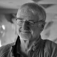 Portrait de John Whitmore, pionnier du coaching d’entreprise, en chemise qui illustre la citation du dessous